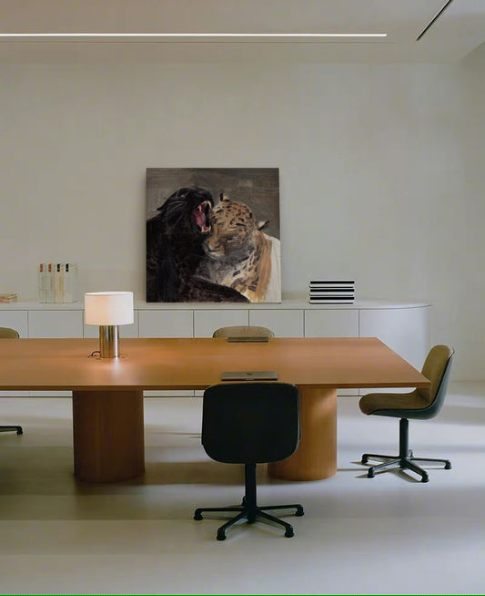 A large square wall art print depicting a black bear and a leopard, displayed in a modern minimalist office setting above a wooden conference table and chairs.