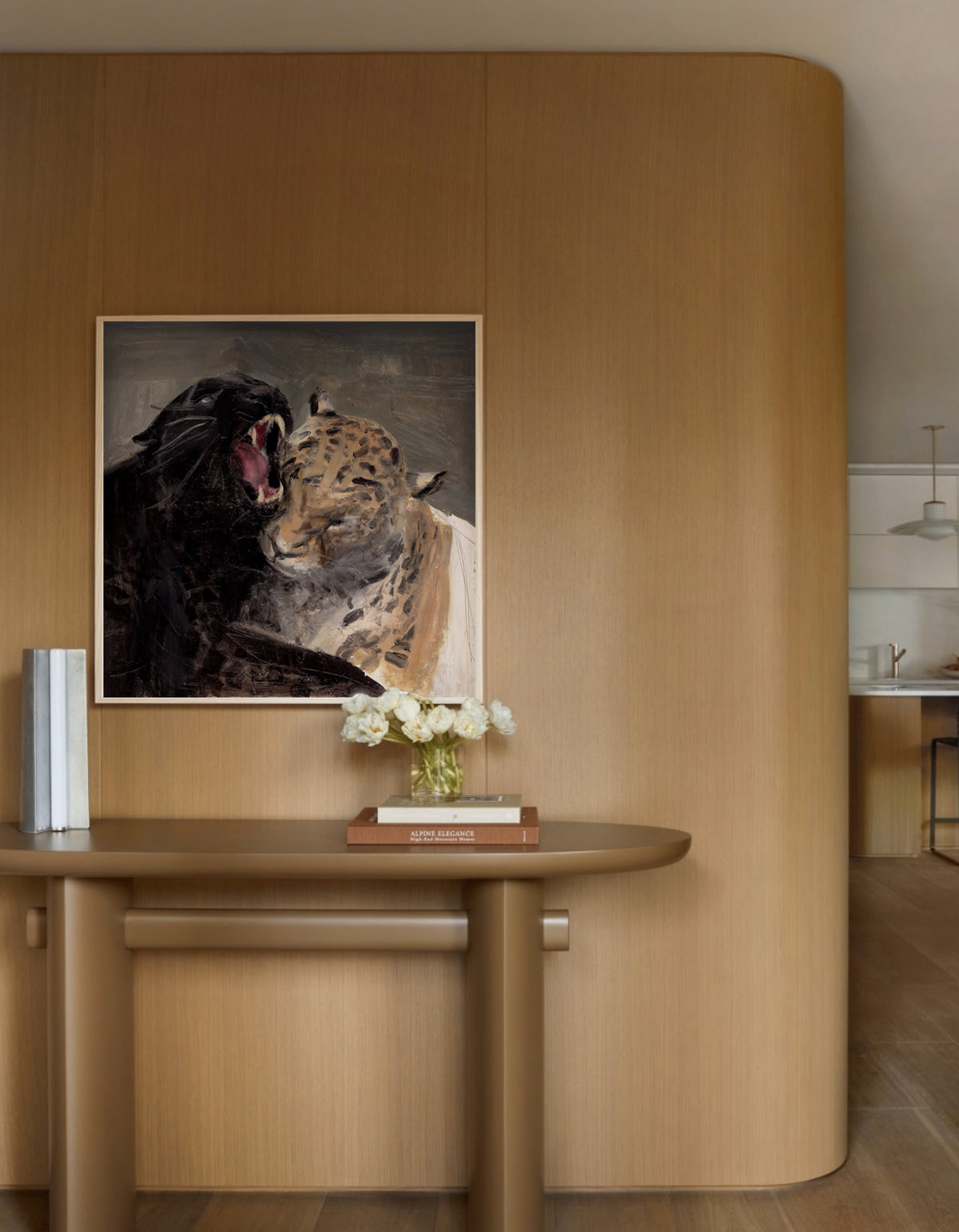 A framed art print depicting a black panther and a leopard, displayed on a curved wooden wall above a matching wooden console table with a vase of white flowers.