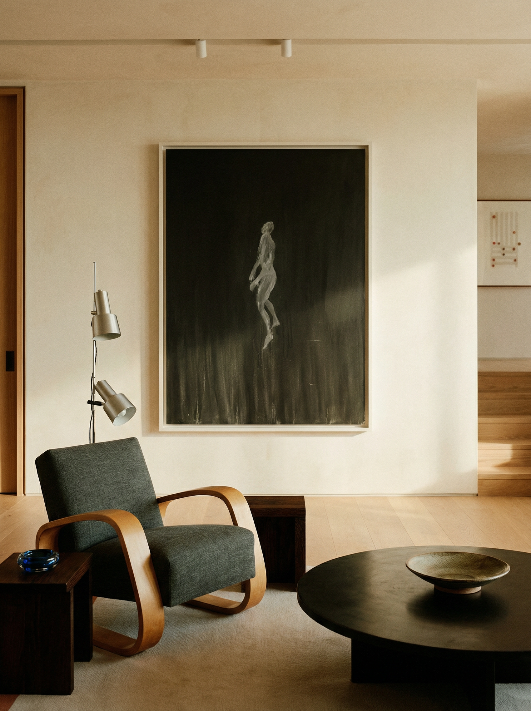 Modern living room with a gray armchair, round coffee table, and large framed artwork on the wall. In the black – Bold Abstract Canvas Wall Art | Large Luxury Print | Brume Art