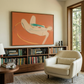 Living room with a beige armchair, bookshelf, and abstract painting on the wall.  Envelope in Orange – Warm Abstract Canvas Art | Luxury Wall Decor | Brume Art