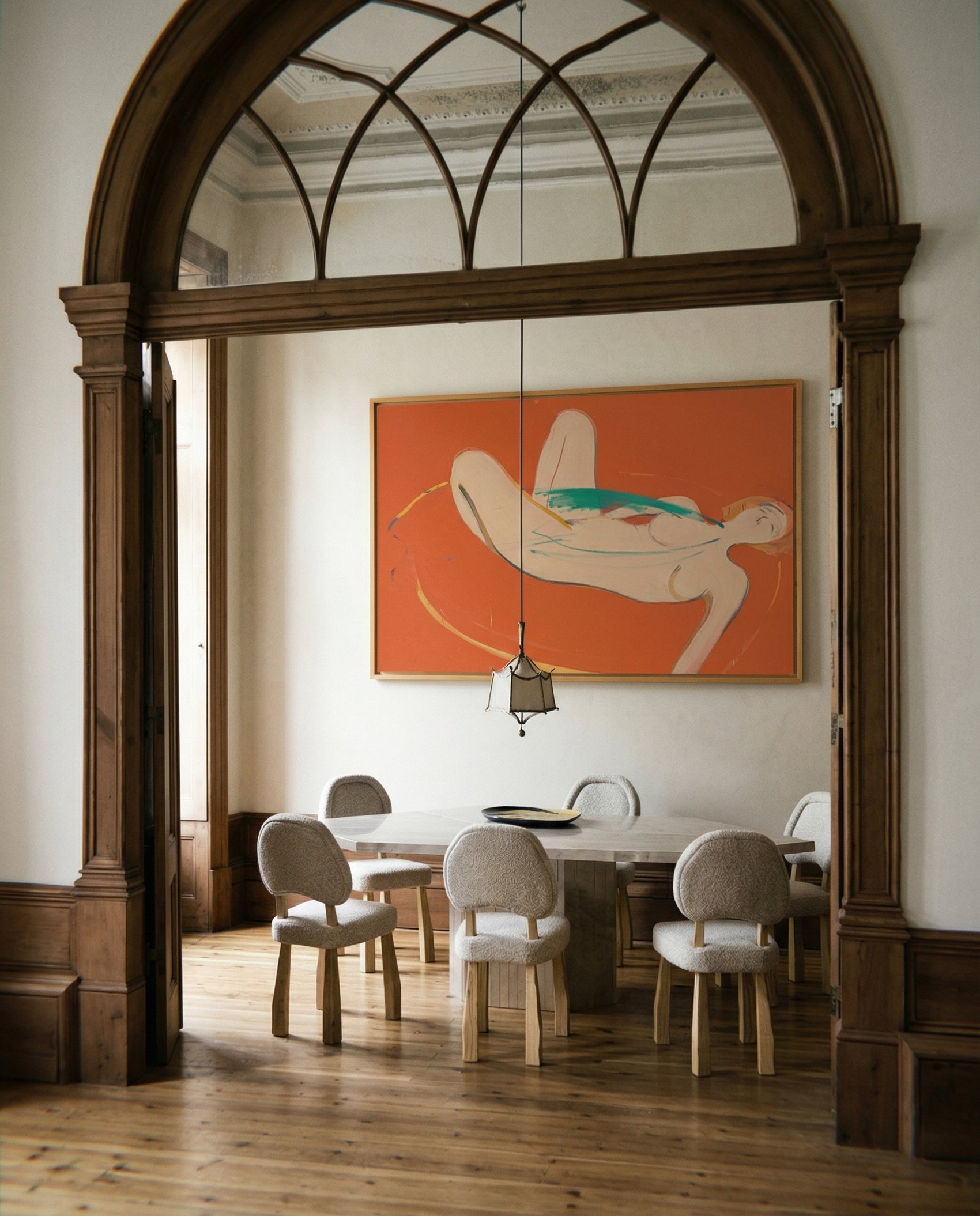 Dining room with wooden floor, chairs, and a large mirror reflecting a painting of a nude figure. Envelope in Orange – Warm Abstract Canvas Art | Luxury Wall Decor | Brume Art