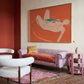 Living room with a pink sofa, white armchair, and abstract painting on the wall.  Envelope in Orange – Warm Abstract Canvas Art | Luxury Wall Decor | Brume Art