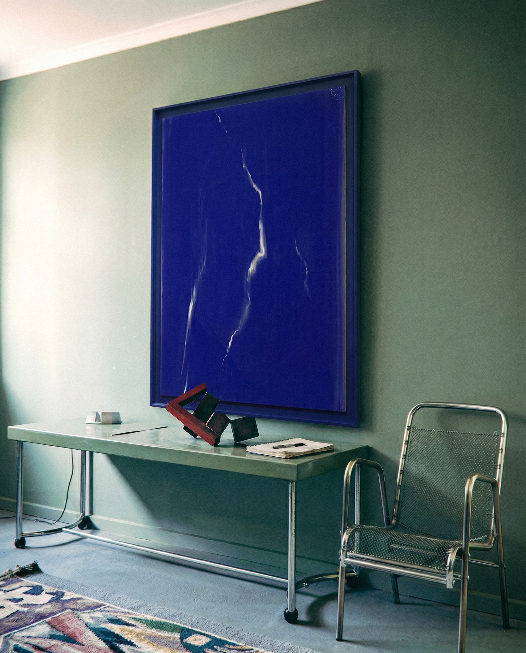 Modern interior with a blue abstract painting on a green wall, a table, and chair.Strike – Bold Abstract Canvas Wall Art | Large Luxury Print | Brume Art