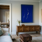 Living room with a large blue abstract painting on the wall, wooden sideboard, and textured rug. Strike – Bold Abstract Canvas Wall Art | Large Luxury Print | Brume Art
