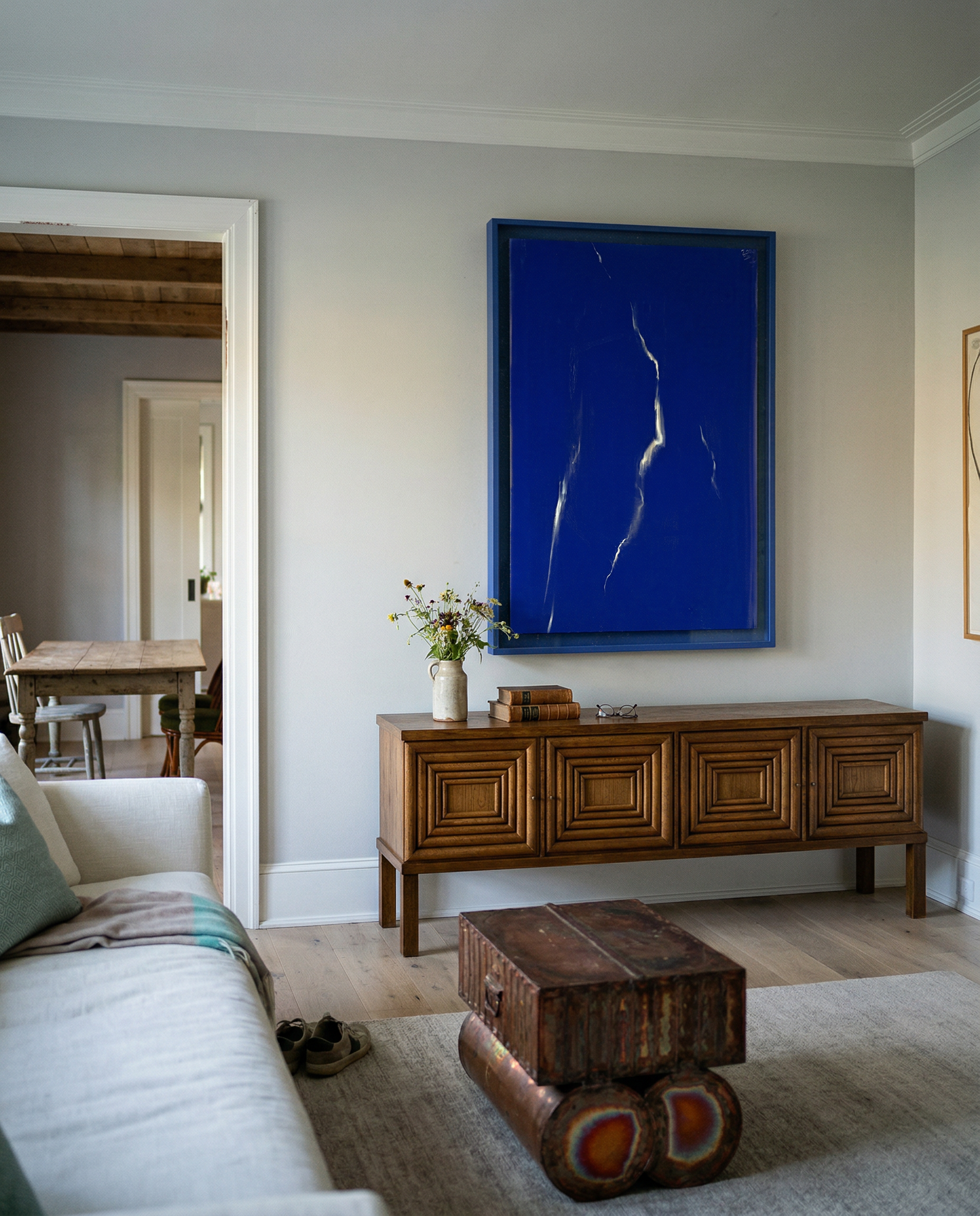 Living room with a large blue abstract painting on the wall, wooden sideboard, and textured rug. Strike – Bold Abstract Canvas Wall Art | Large Luxury Print | Brume Art