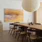 Dining room with wooden table and chairs, abstract painting on the wall, and pendant light. Field Yellow – Landscape Canvas Wall Art | Large Luxury Print | Brume Art