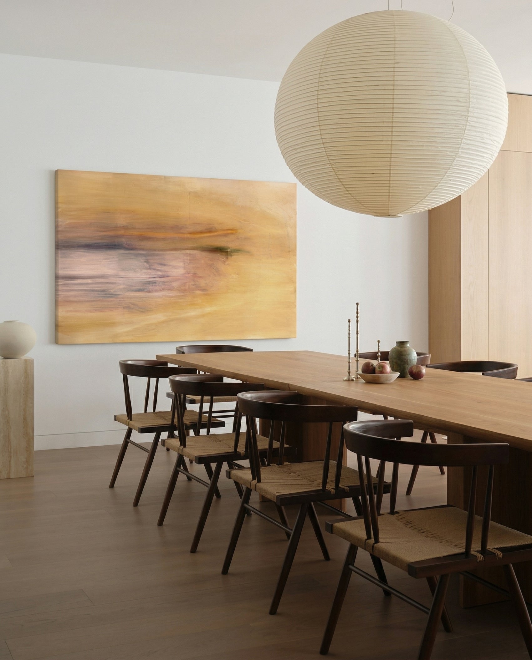 Dining room with wooden table and chairs, abstract painting on the wall, and pendant light. Field Yellow – Landscape Canvas Wall Art | Large Luxury Print | Brume Art