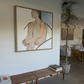 Living room with a large abstract painting on the wall, wooden bench, and indoor plant. Held body – Figurative Canvas Wall Art | Contemporary Luxury Print | Brume Art