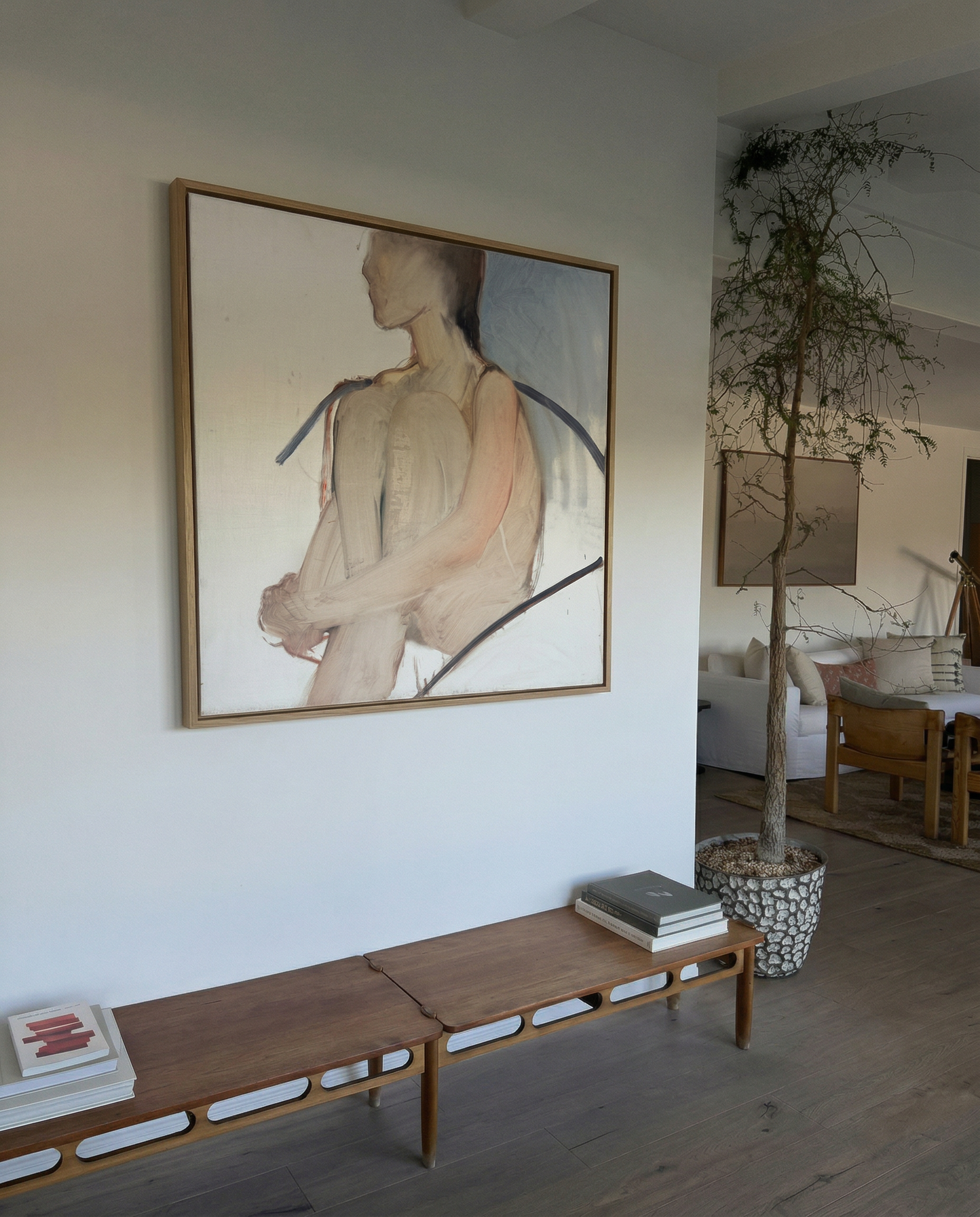 Living room with a large abstract painting on the wall, wooden bench, and indoor plant. Held body – Figurative Canvas Wall Art | Contemporary Luxury Print | Brume Art