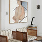 Living room with wicker furniture, striped cushions, and a large framed painting on the wall. Held body – Figurative Canvas Wall Art | Contemporary Luxury Print | Brume Art