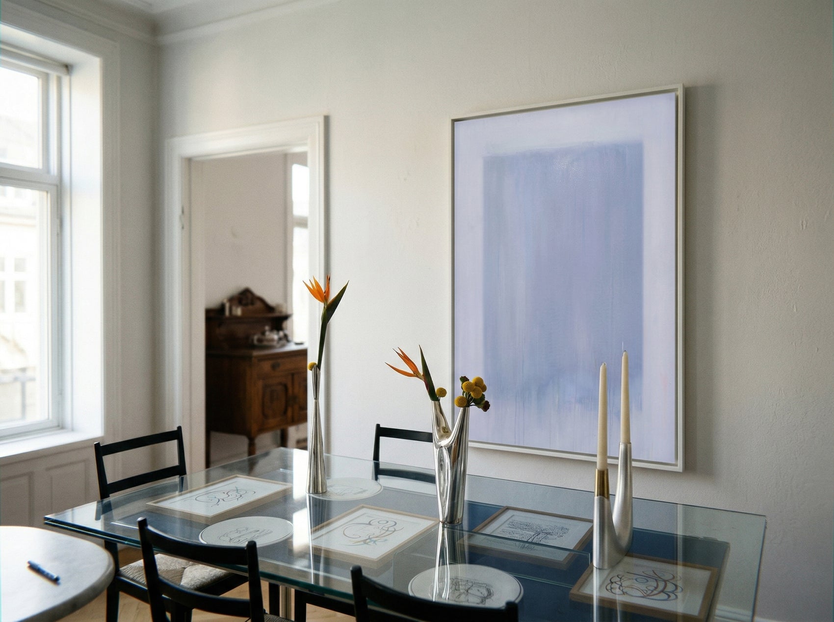 Dining room with a glass table, chairs, and a large abstract painting on the wall. Frame – Bold Abstract Canvas Wall Art | Large Luxury Print | Brume Art