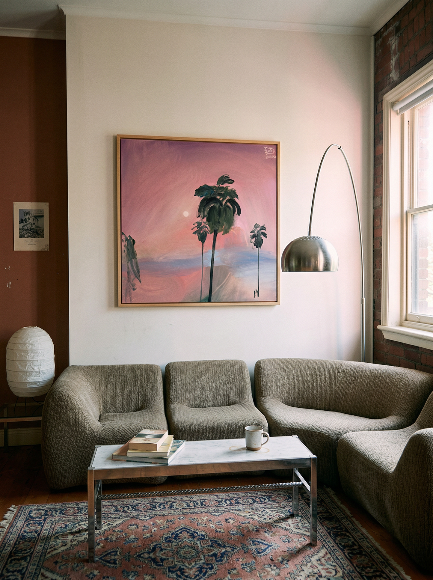 Living room with a gray sofa, coffee table, and wall art of palm trees and a sunset. Palm tree – Landscape Canvas Wall Art | Large Luxury Print | Brume Art 