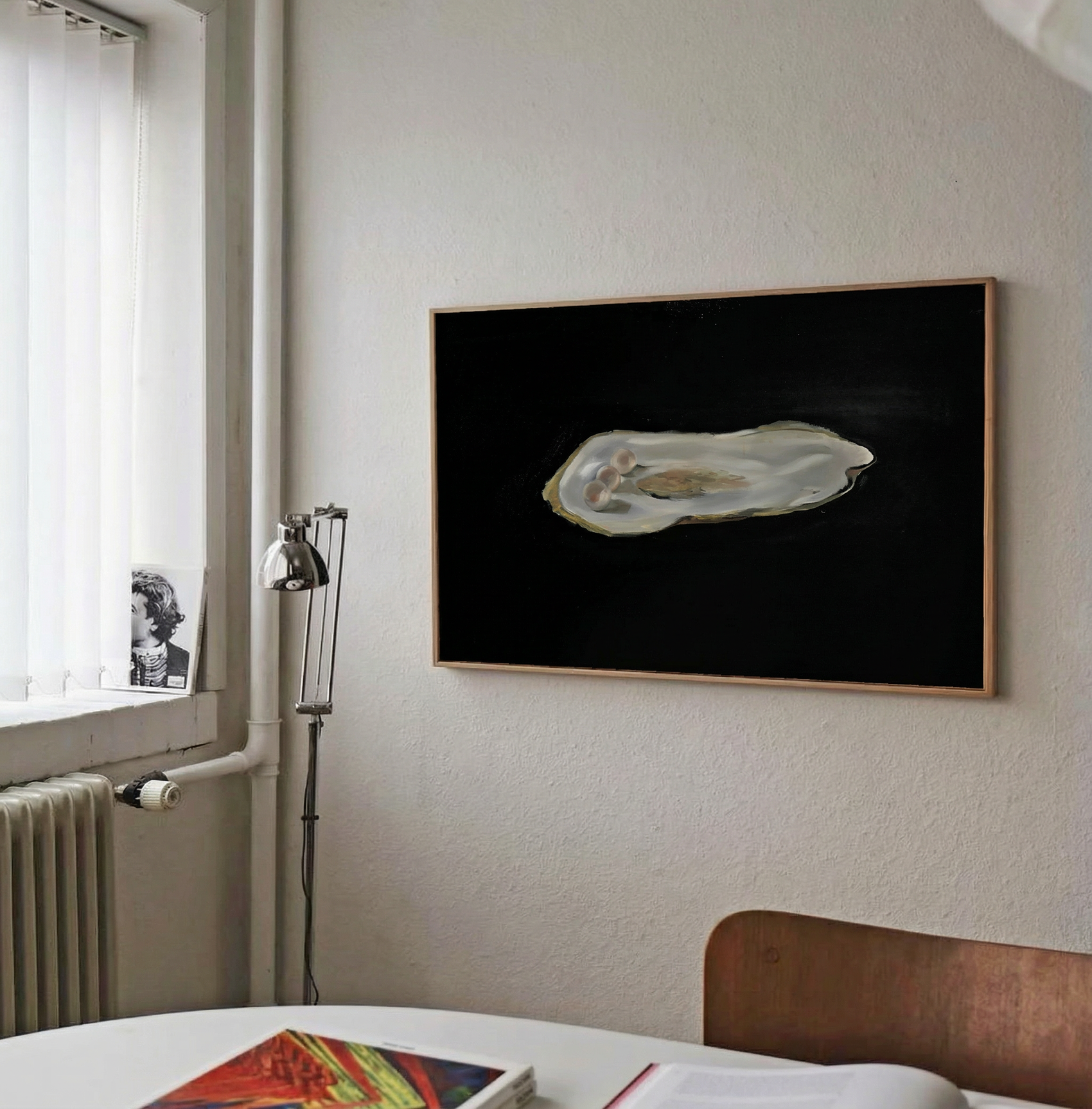 Framed artwork of an oyster on a black background in a room with a window and radiator. Pearl 2 – Elegant Abstract Canvas Wall Art | Luxury Giclée Print | Brume Art| Luxury Wall Decor | Large Canvas Wall Art | Oversized Wall Hanging-Brume art
