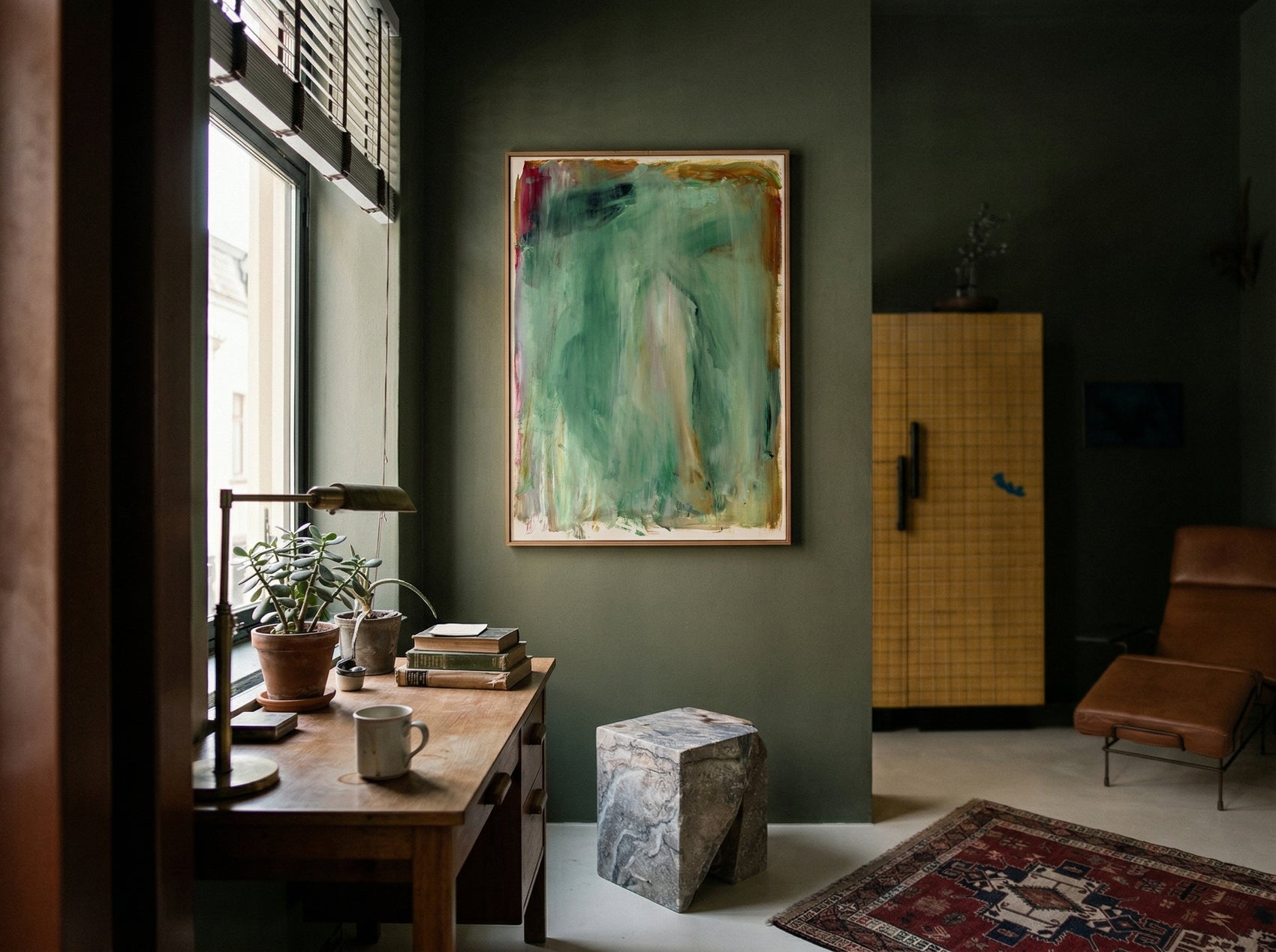 Modern interior with a painting on the wall, wooden table, and chair. Abstract painting with green and brown tones on a white background Field green 2 – Abstract Canvas Wall Art | Large Luxury Print | Brume Art