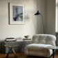 Modern living room with a white armchair, wooden stool, and framed artwork on the wall. Orchid – Botanical Canvas Wall Art | Large Luxury Print | Brume Art