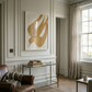 Living room with a brown armchair, glass table, and abstract art on the wall. Golden Bird – Elegant Nature Canvas Print | Luxury Wall Art | Brume Art