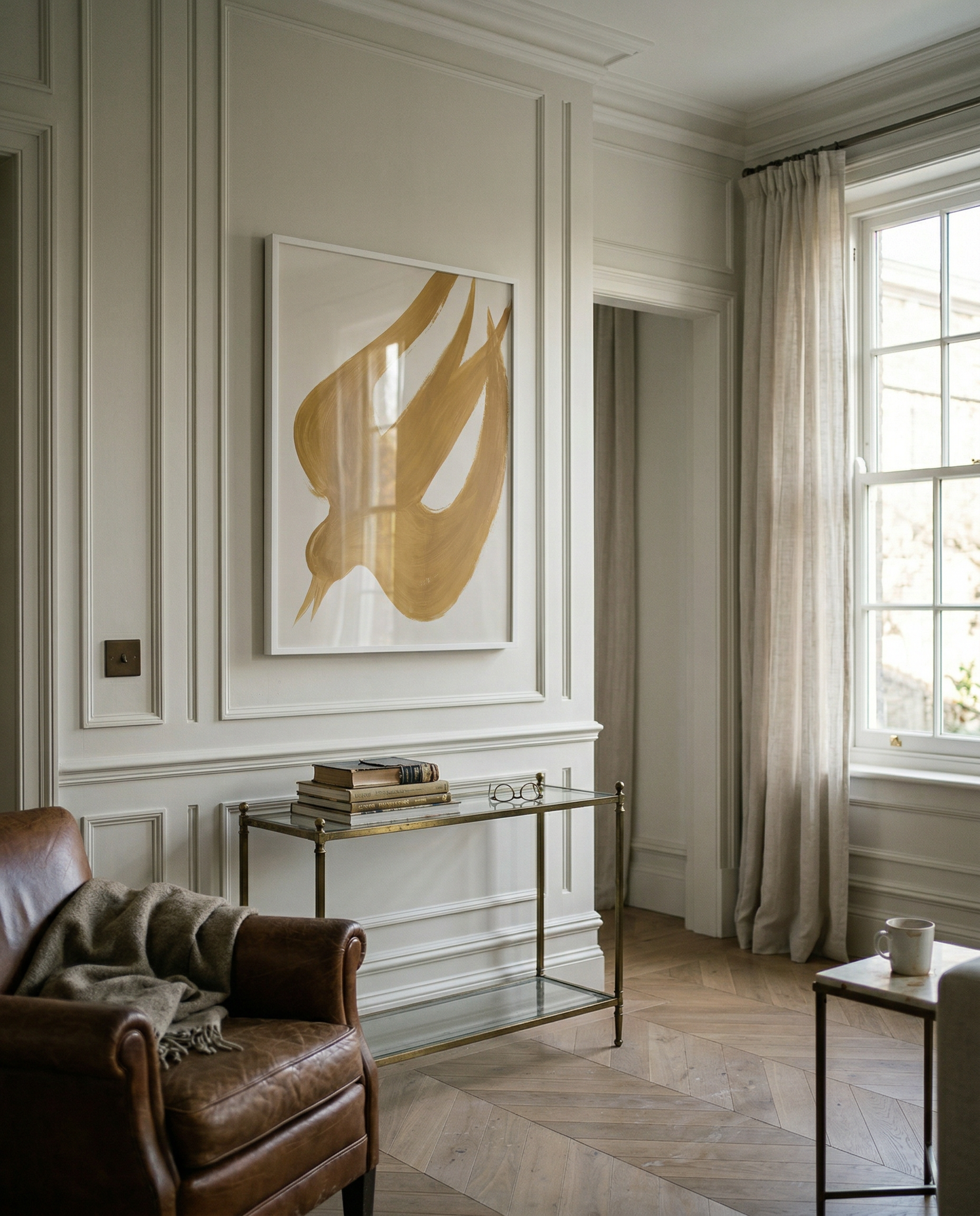 Living room with a brown armchair, glass table, and abstract art on the wall. Golden Bird – Elegant Nature Canvas Print | Luxury Wall Art | Brume Art