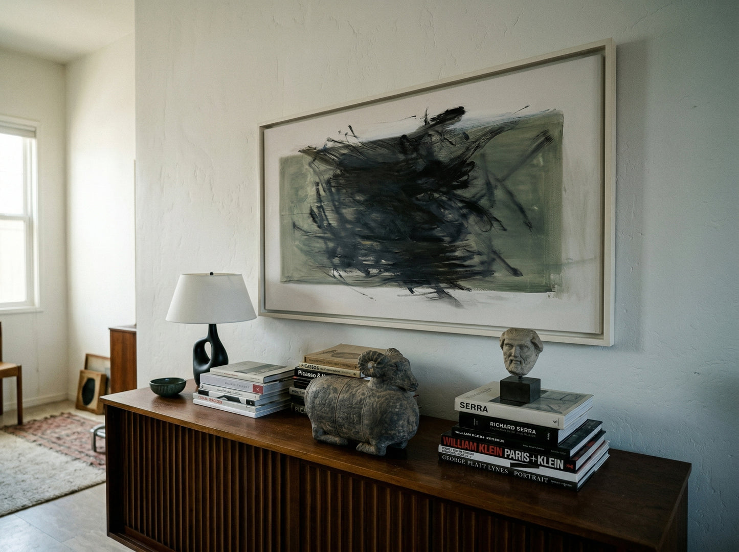 Wooden console table with books, sculptures, and a lamp against a wall with abstract art. Tension 2 – Bold Abstract Canvas Print | Large Luxury Wall Art | Brume Art