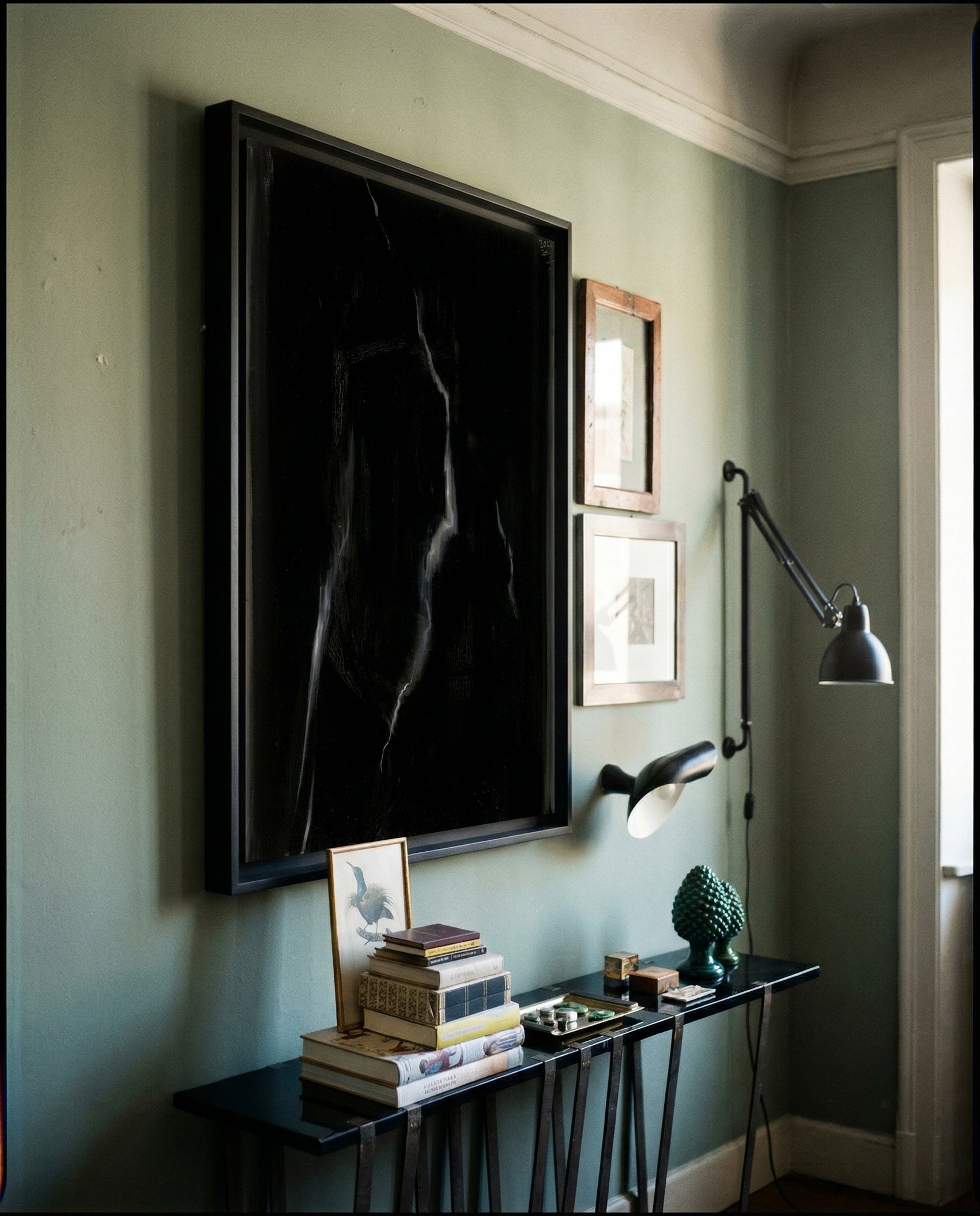 Artistic interior with a large framed black and white silhouette on a green wall, accompanied by smaller framed pictures and a table with books and decor items. Strike 2 – Bold Abstract Canvas Wall Art | Premium Luxury Print | Brume Art