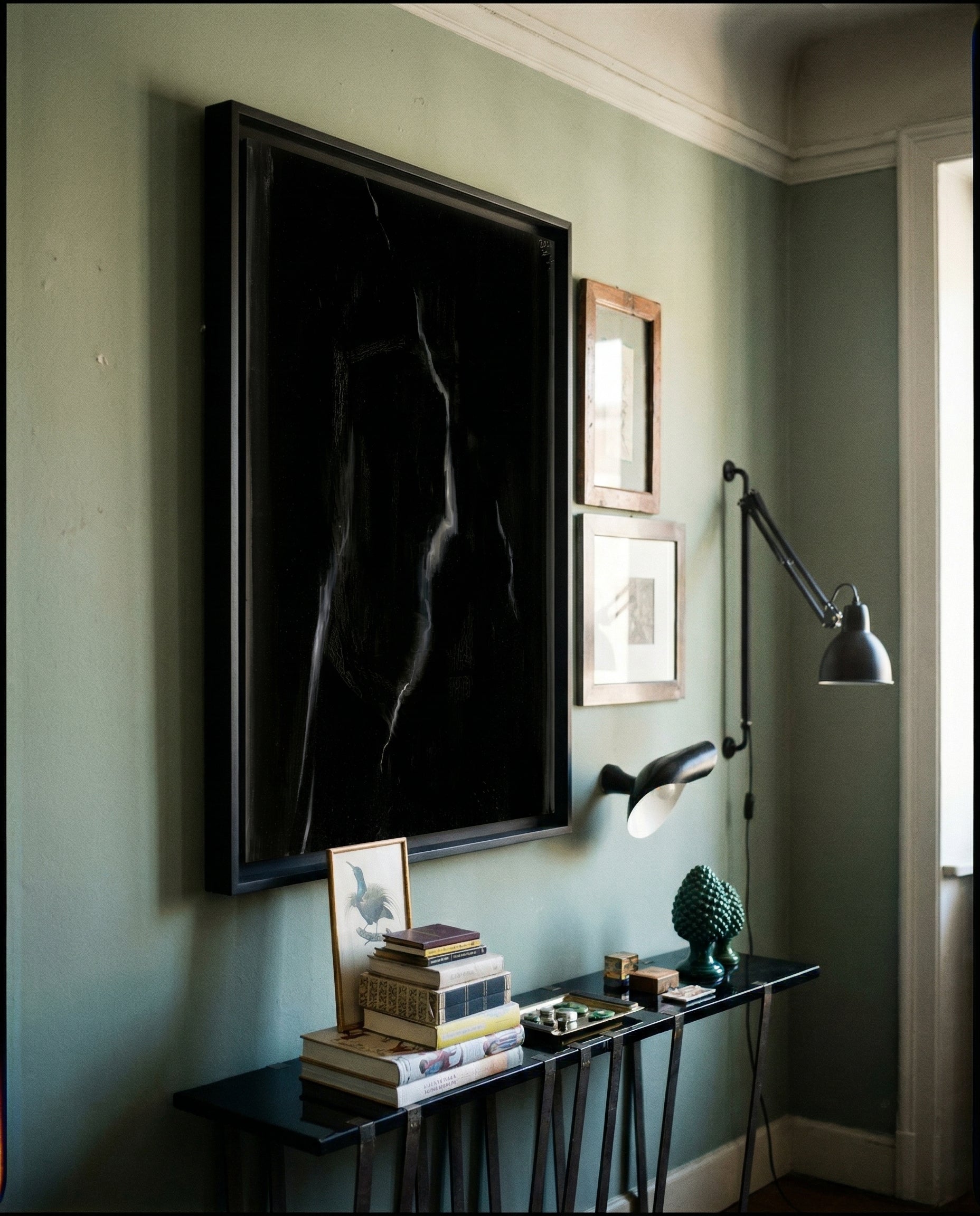 Artistic interior with a large framed black and white silhouette on a green wall, accompanied by smaller framed pictures and a table with books and decor items. Strike 2 – Bold Abstract Canvas Wall Art | Premium Luxury Print | Brume Art