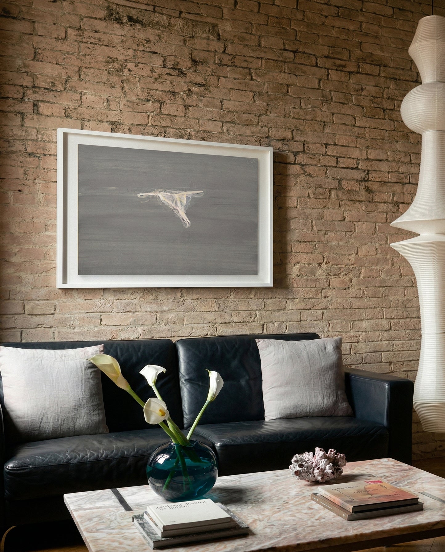 Living room with a black sofa, framed artwork on a brick wall, and decorative items on a coffee table. Thong - Minimalist Abstract Canvas Art | Large Luxury Wall Print | Brume Art