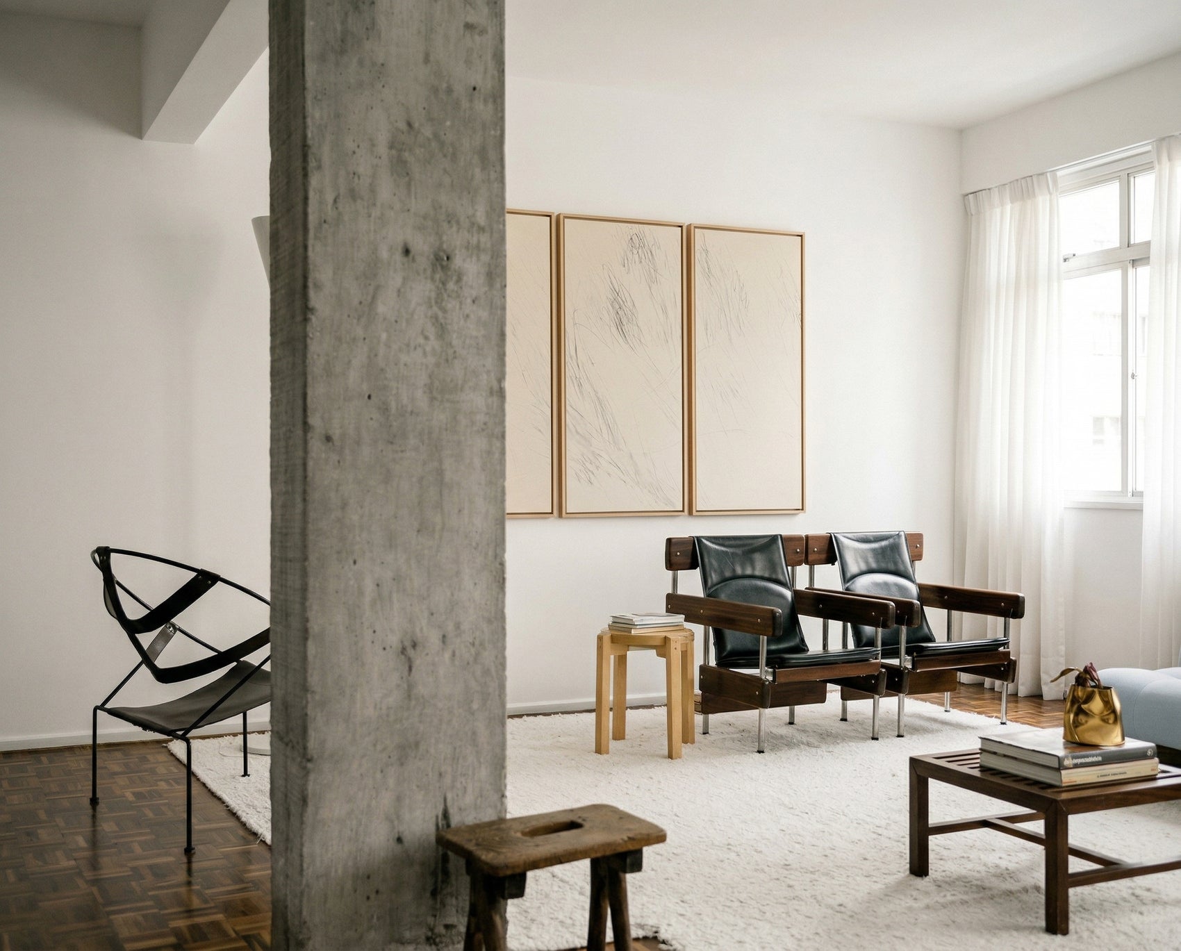 Modern living room with a concrete pillar, black chair, wooden stool, and a sofa with cushions. Black lines 2 – Bold Abstract Canvas Wall Art | Premium Luxury Print | Brume Art| Luxury Wall Decor | Large Canvas Wall Art | Oversized Wall Hanging-Brume art