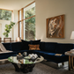 Modern living room with a navy blue sectional sofa, round glass coffee table, and abstract painting on the wall. Noise 4 – Textured Abstract Canvas Art | Premium Luxury Wall Decor | Brume Art | Luxury Wall Decor | Large Canvas Wall Art | Oversized Wall Hanging-Brume art