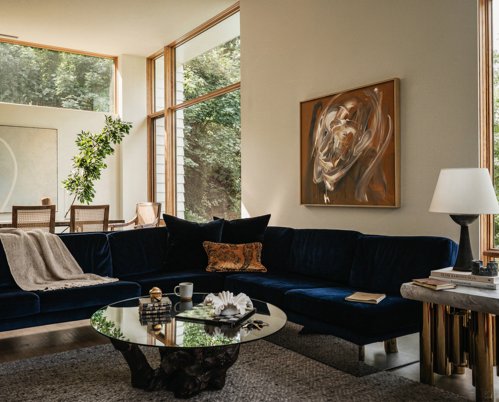 Modern living room with a navy blue sectional sofa, round glass coffee table, and abstract painting on the wall. Noise 4 – Textured Abstract Canvas Art | Premium Luxury Wall Decor | Brume Art | Luxury Wall Decor | Large Canvas Wall Art | Oversized Wall Hanging-Brume art