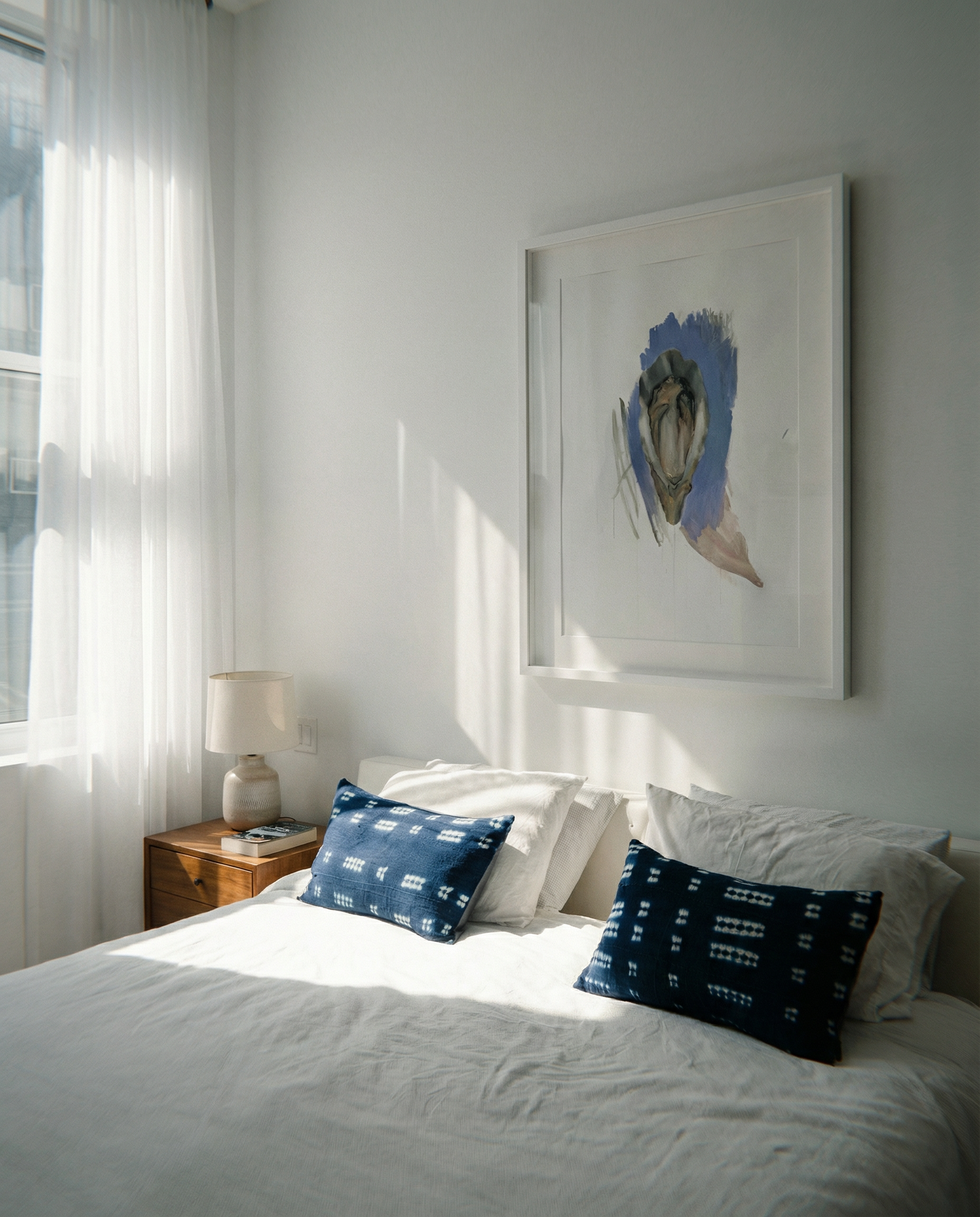 Bedroom with white bedding and blue pillows, framed artwork on the wall. oyster – Elegant Abstract Canvas Wall Art | Luxury Giclée Print | Brume Art| Luxury Wall Decor | Large Canvas Wall Art | Oversized Wall Hanging-Brume art