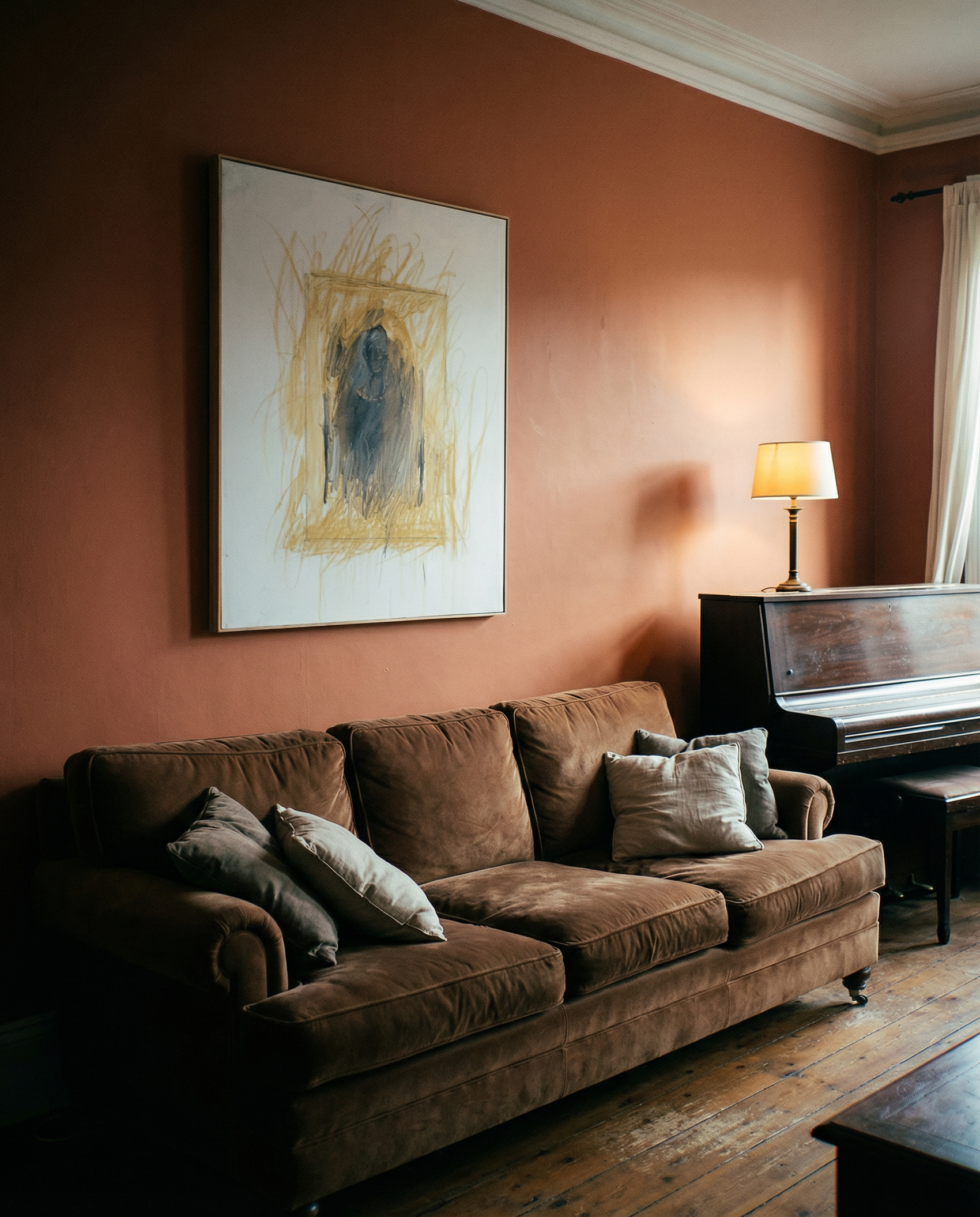 Brown sofa with cushions in a room with a painting and lamp on an orange wall. Fading figure – Bold Abstract Canvas Print | Large Luxury Wall Art | Brume Art