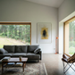 Modern living room with a gray sofa, wooden coffee table, and large windows overlooking a forest. Fading figure – Bold Abstract Canvas Print | Large Luxury Wall Art | Brume Art