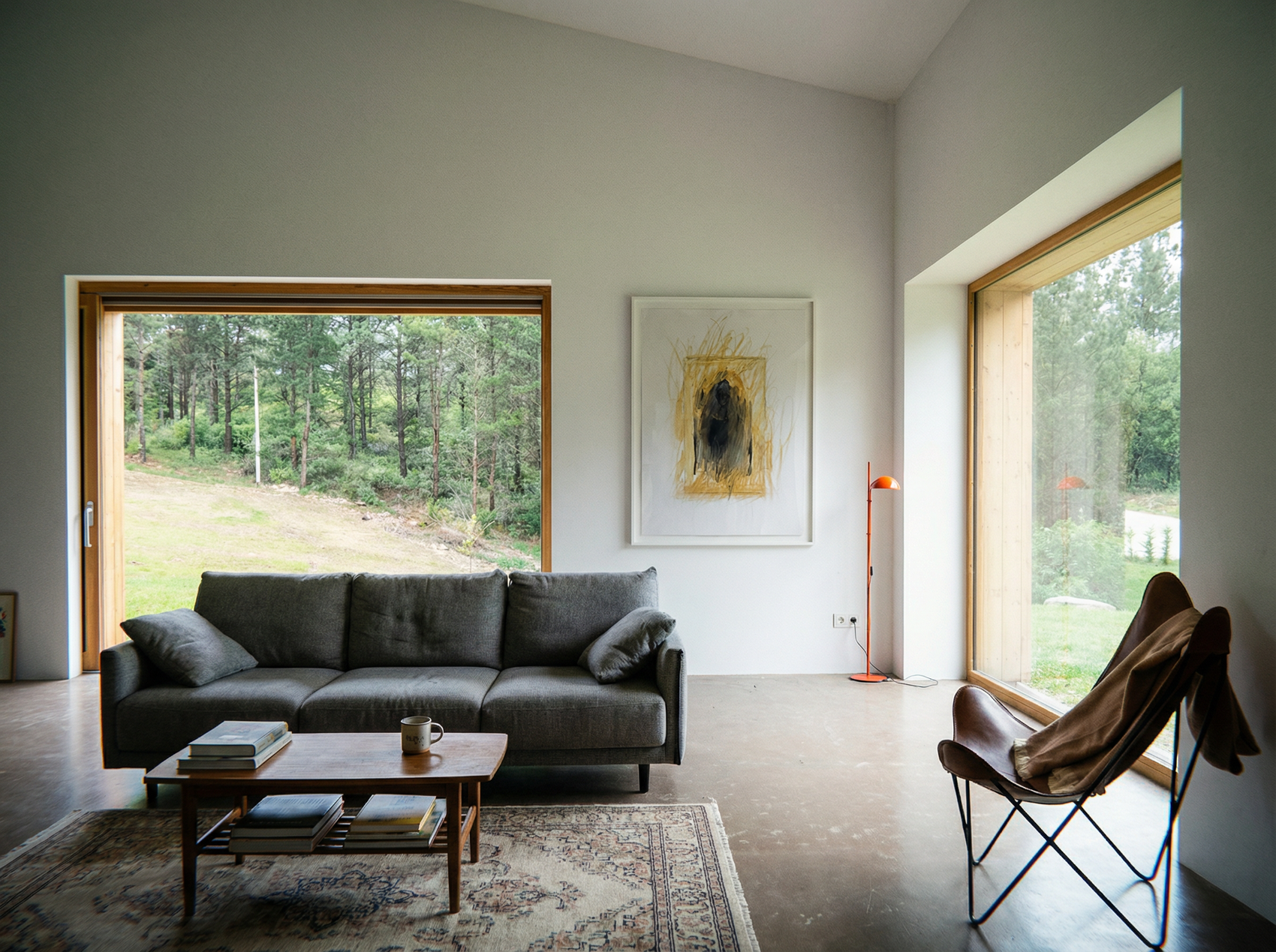 Modern living room with a gray sofa, wooden coffee table, and large windows overlooking a forest. Fading figure – Bold Abstract Canvas Print | Large Luxury Wall Art | Brume Art
