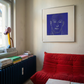 Living room with a red sofa, books, and a painting of a face on the wall. Presence 4 – Figurative Abstract Canvas Print | Large Luxury Wall Art | Brume Art