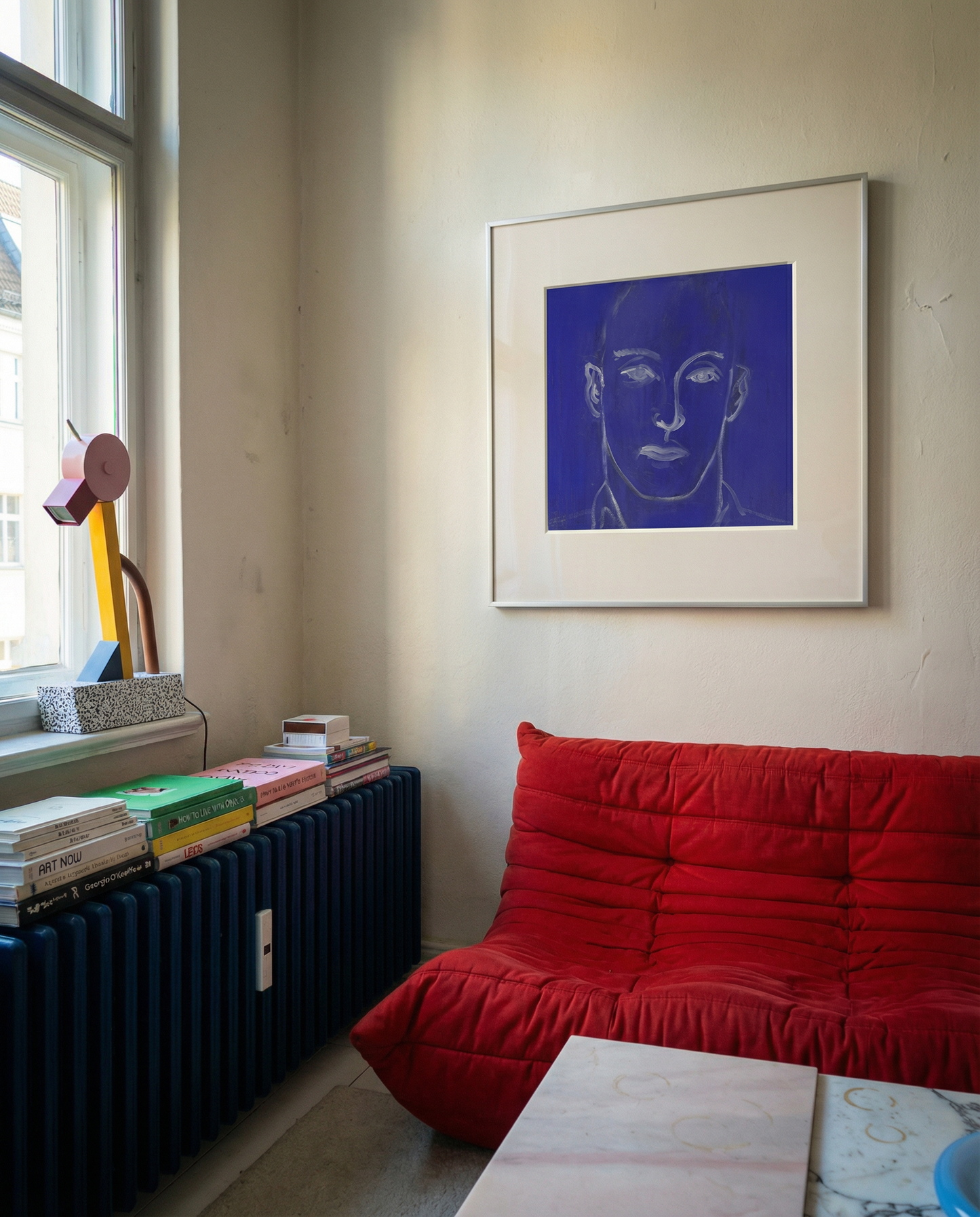 Living room with a red sofa, books, and a painting of a face on the wall. Presence 4 – Figurative Abstract Canvas Print | Large Luxury Wall Art | Brume Art