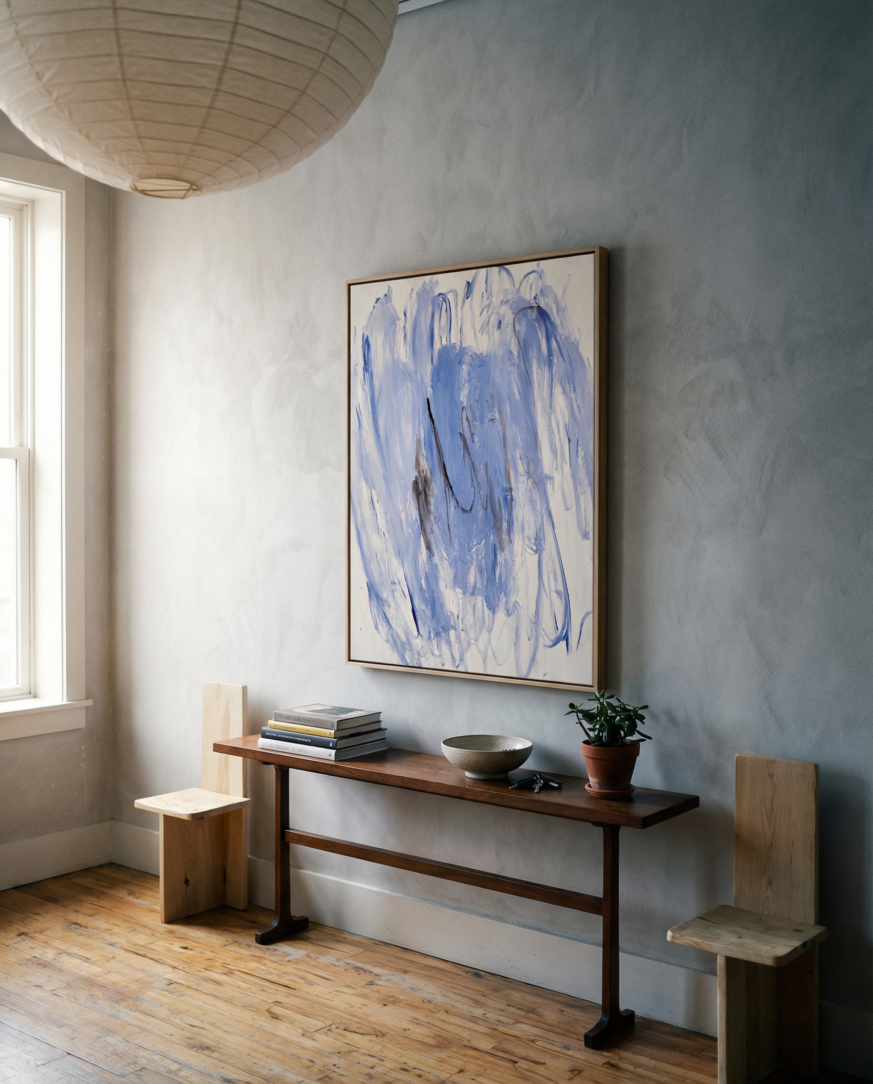 Nook with wooden bench, abstract blue painting, and potted plant against a light gray wall. Veil – Contemporary Abstract Canvas | Oversized Luxury Wall Art | Brume Art | Luxury Wall Decor | Large Canvas Wall Art | Oversized Wall Hanging-Brume art