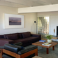 Living room with a brown sectional sofa, wooden coffee table, and framed artwork on the wall. Away – Minimalist Abstract Canvas Art | Large Luxury Wall Decor | Brume Art