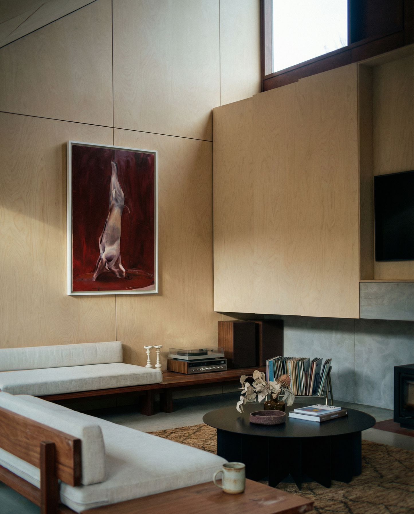 Modern living room with wooden walls, a sofa, coffee table, and decorative items. Painting of a dog standing on its hind legs against a red background Suspension – Nature Canvas Wall Art | Large Luxury Print | Brume Art