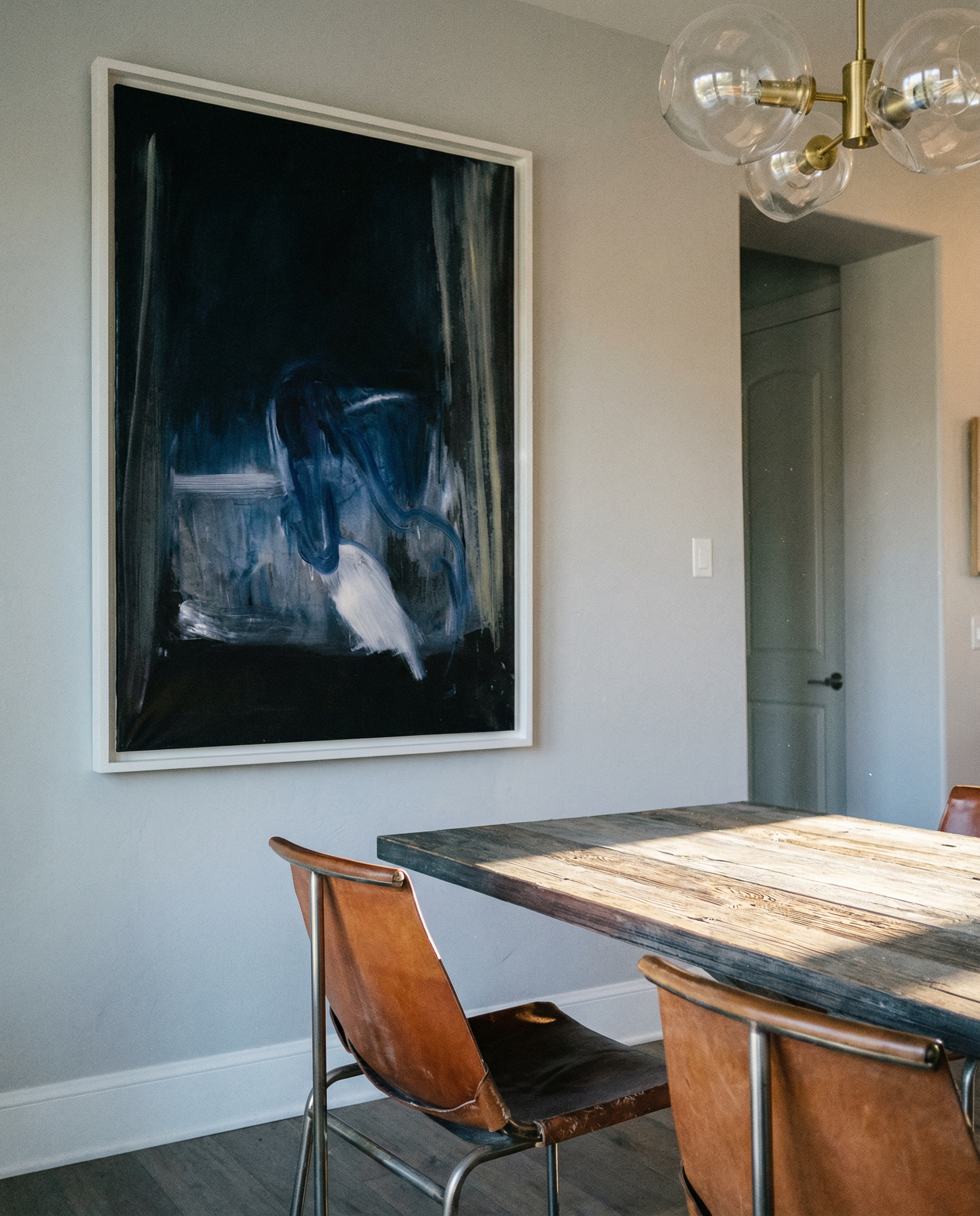 Dining room with a large abstract painting on the wall, wooden table, and chairs. Field black – Landscape Canvas Wall Art | Large Luxury Print | Brume Art