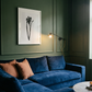 Blue sofa in a room with green walls and a framed picture. Blossom – Botanical Canvas Wall Art | Large Luxury Print | Brume Art
