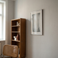 Wooden bookshelf with decorative items next to a wall with a framed picture in a room with natural light. fade 4– Bold Abstract Canvas Print | Large Luxury Wall Art | Brume Art| Luxury Wall Decor | Large Canvas Wall Art | Oversized Wall Hanging-Brume art