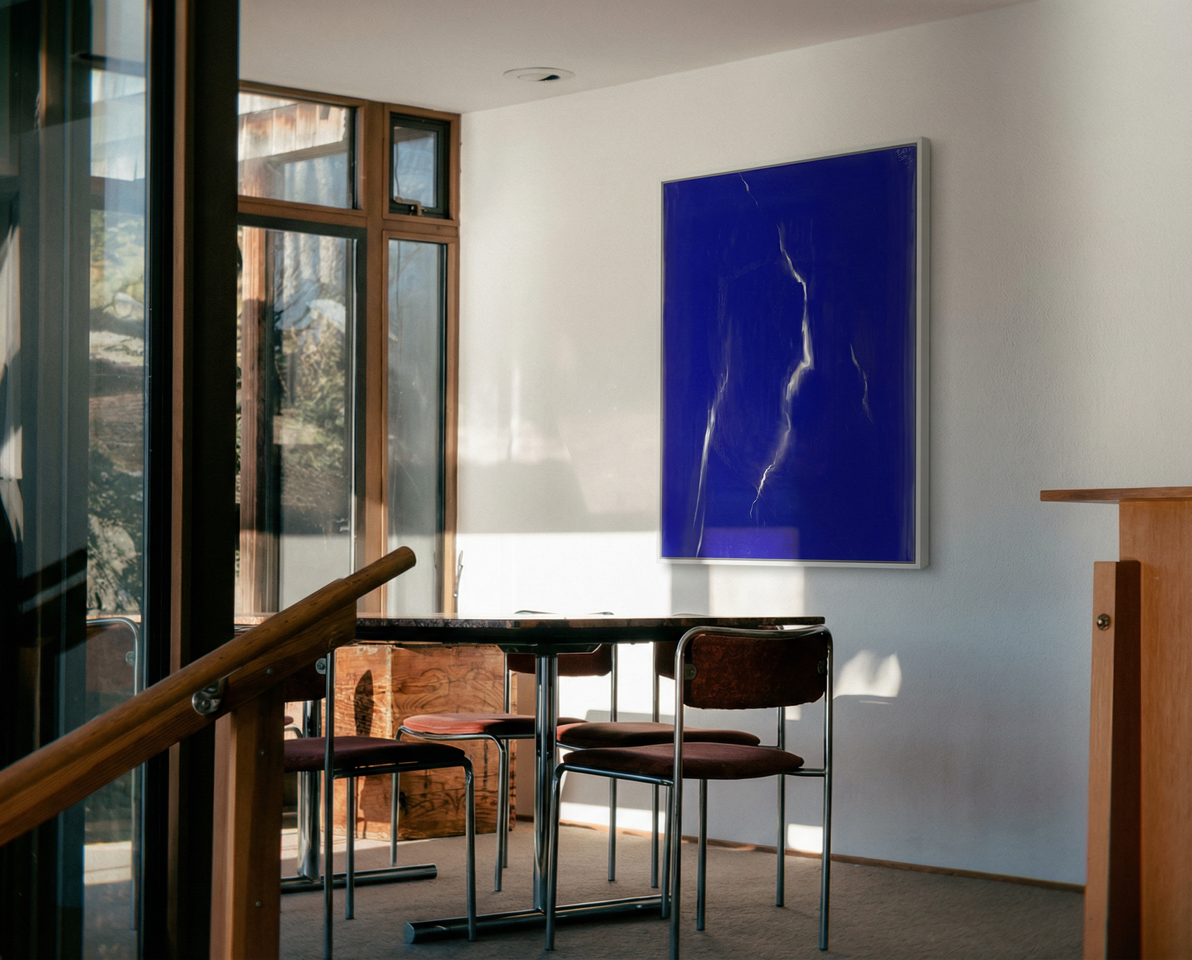 Modern interior with a blue abstract painting on a white wall, a dining table, and chairs. Strike – Bold Abstract Canvas Wall Art | Large Luxury Print | Brume Art