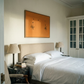 Neatly made bed in a bedroom with a painting on the wall and side tables. Marks – Bold Abstract Canvas Wall Art | Premium Luxury Print | Brume Art
