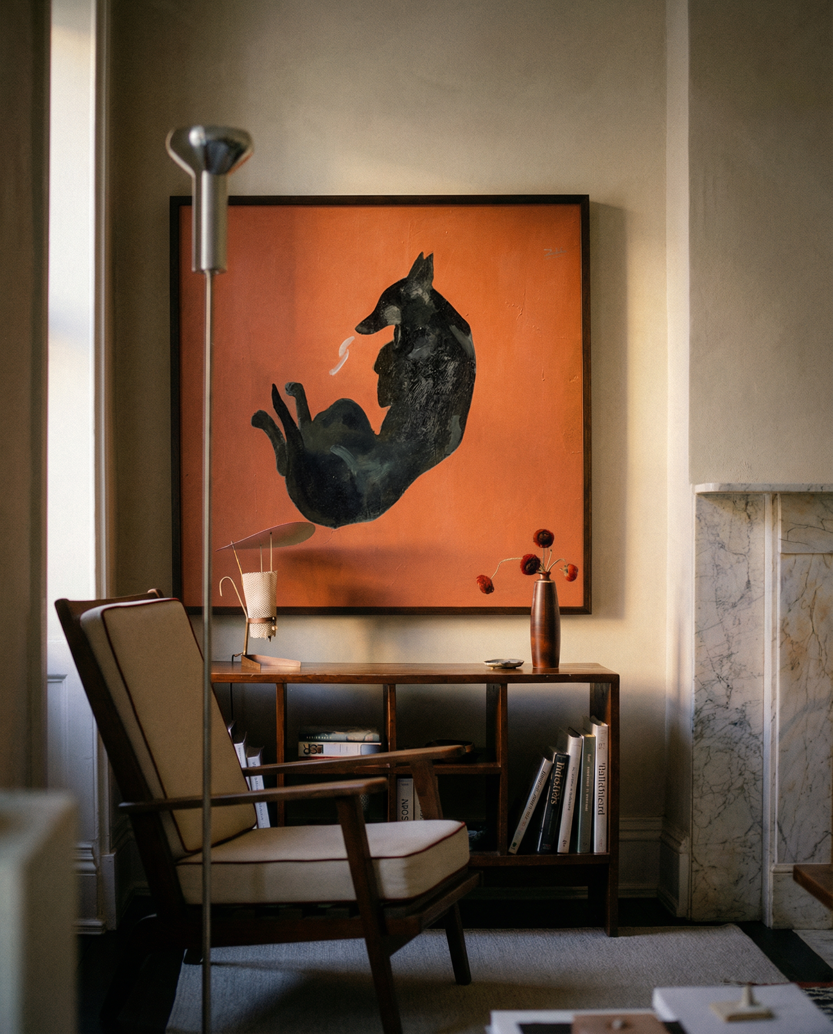 Living room with a black dog painting on an orange background, a chair, and a side table. Black dog – Contemporary Animal Canvas Art | Luxury Wall Decor | Brume Art | Luxury Wall Decor | Large Canvas Wall Art | Oversized Wall Hanging-Brume art