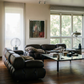 Modern living room with dark leather sofas, a glass coffee table, and large windows. Field green – Bold Abstract Canvas Wall Art | Large Luxury Print | Brume Art 