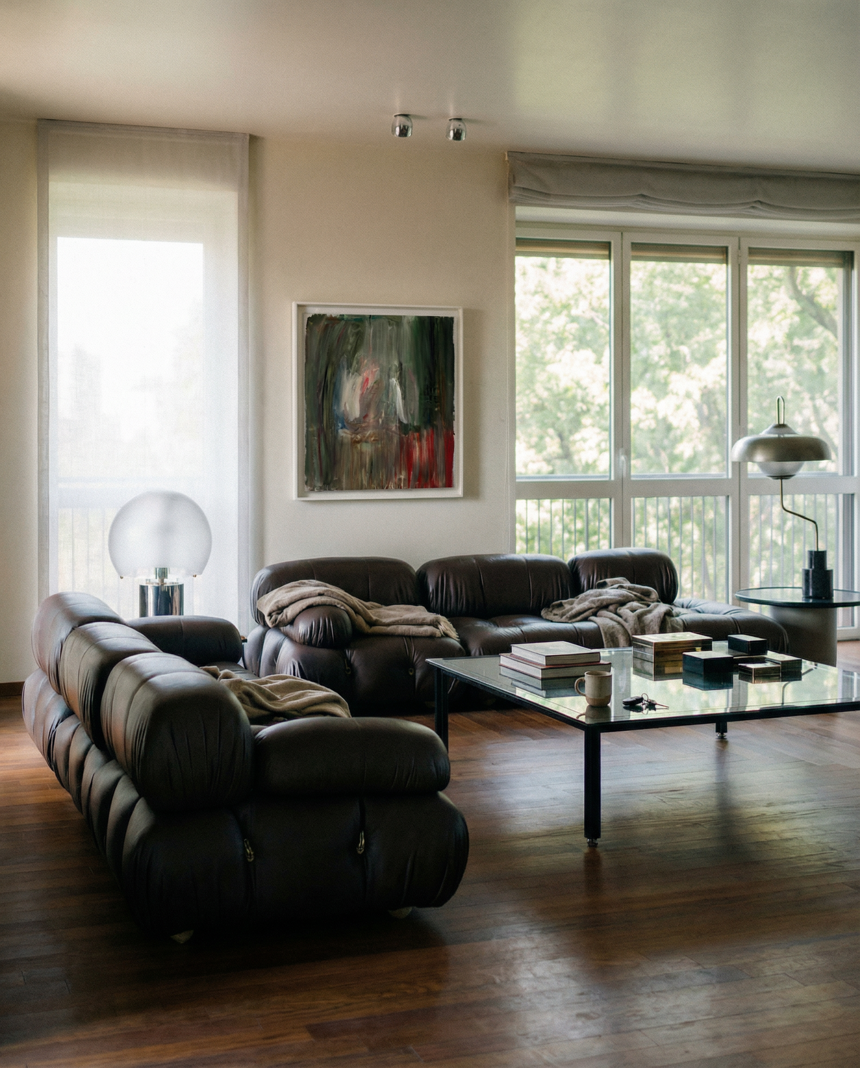 Modern living room with dark leather sofas, a glass coffee table, and large windows. Field green – Bold Abstract Canvas Wall Art | Large Luxury Print | Brume Art 