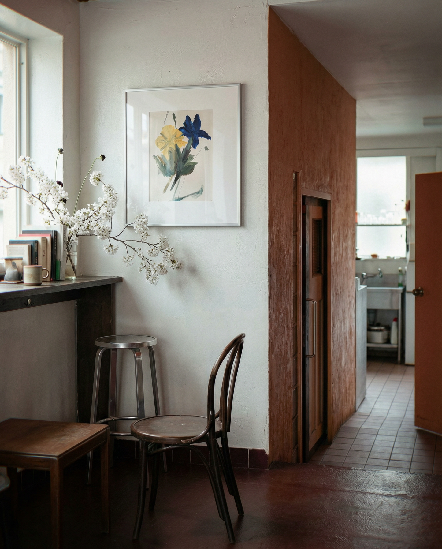 Small kitchen with a bar stool, chair, and floral artwork on the wall. Blossom 2 – Botanical Canvas Wall Art | Premium Luxury Print | Brume Art