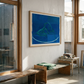 Modern interior with a large blue abstract painting on a white wall, wooden bench, and table.
