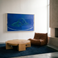 Modern living room with a brown leather chair, wooden coffee table, and abstract blue painting on the wall.