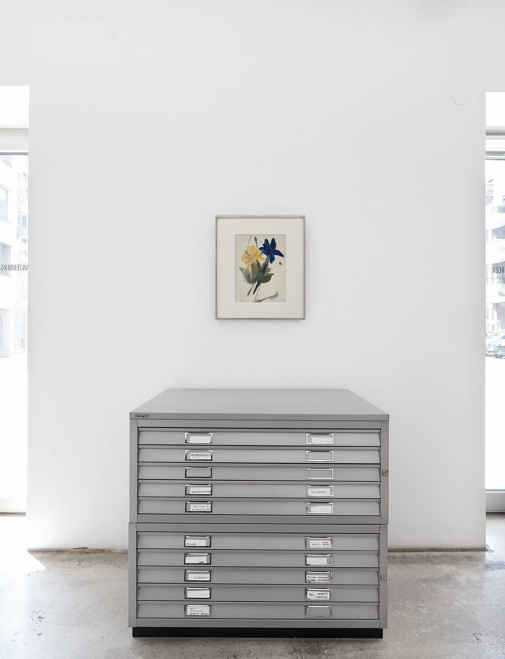 Gray metal filing cabinet against a white wall with a framed picture of flowers. Blossom 2 – Botanical Canvas Wall Art | Premium Luxury Print | Brume Art