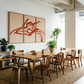 Dining area with wooden table and chairs, large abstract painting on the wall, and plants.